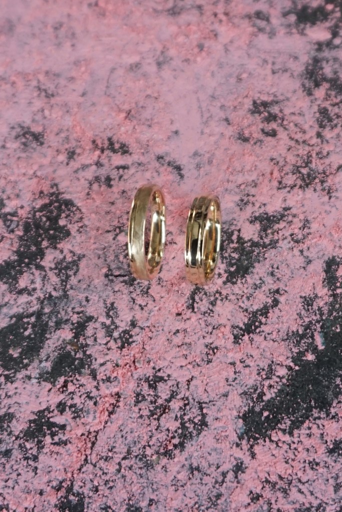 Eheringe in 750/ Roségold in Handarbeit gefertigt. Ein Ring mit Sägeschnitt auf einem Drittel, poliert und eismatt. Der zweite Ring mit einem hochstehenden mittleren Drittel, poliert als Unikat. Fotografiert auf rosa Kreide auf der Feinkost in Leipzig